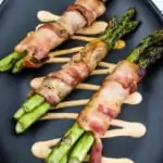 bacon-wrapped grilled asparagus on a black plate