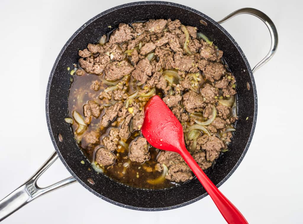 adding sauce and broth to beef