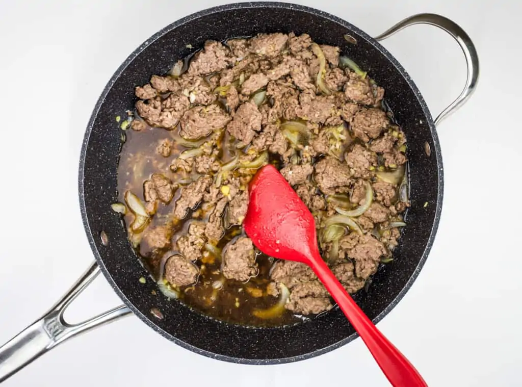 adding sauce and broth to beef