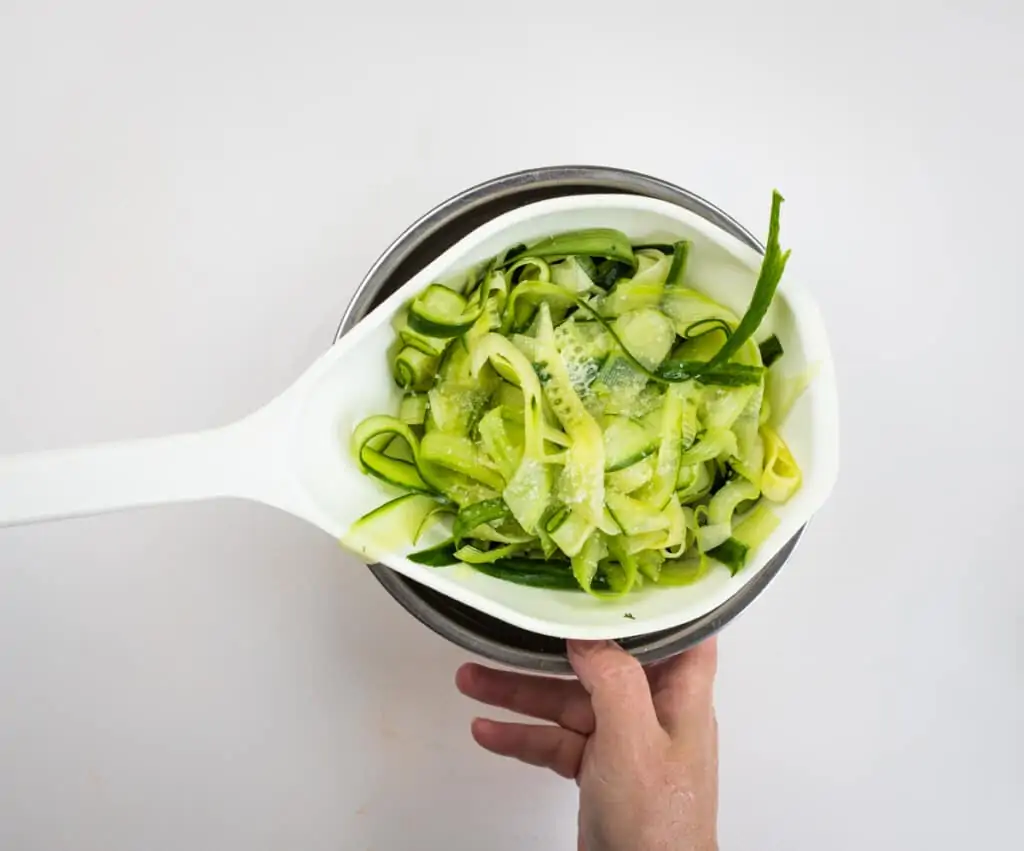 salted cucumber set over a bowl to drain