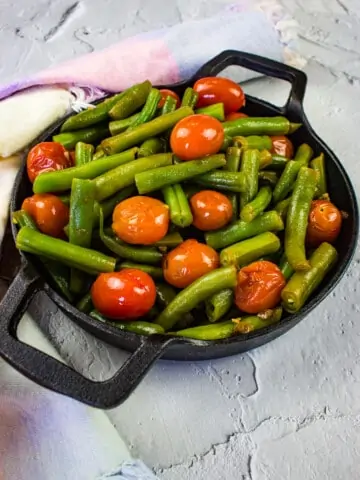 green beans & tomatoes in a black serving dish