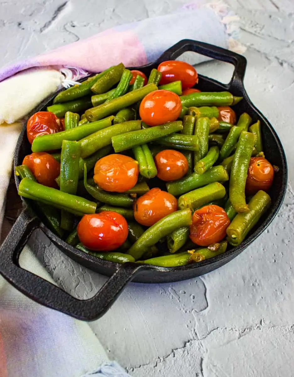 green beans & tomatoes in a black serving dish