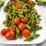 sauteed green beans and tomatoes on a white serving platter