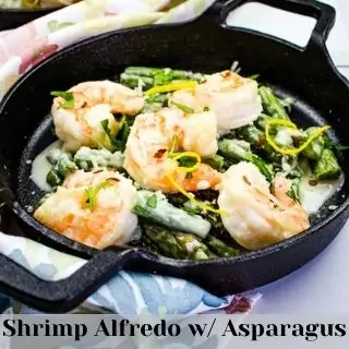 Shrimp Alfredo with Asparagus in a black serving dish.