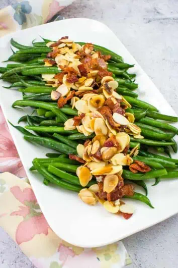 green beans almondine with bacon on a white platter