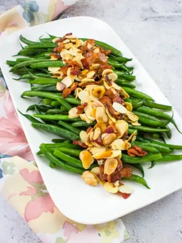 green beans almondine with bacon on a white platter