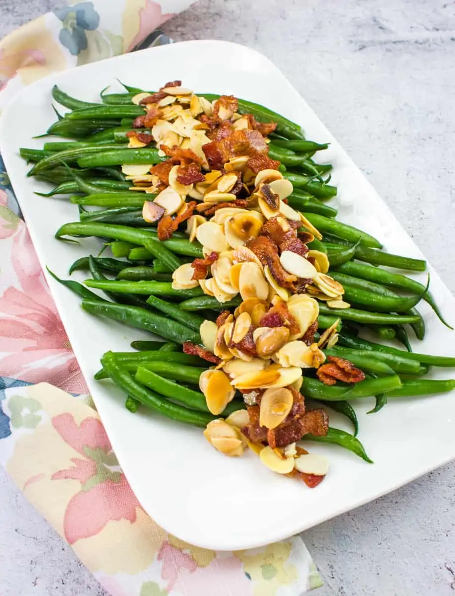 green beans almondine with bacon on a white platter