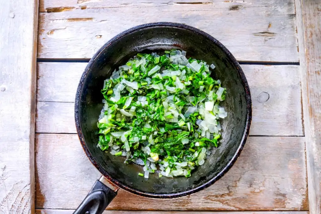 sauteeing onions and spinach for stuffed turkey roll