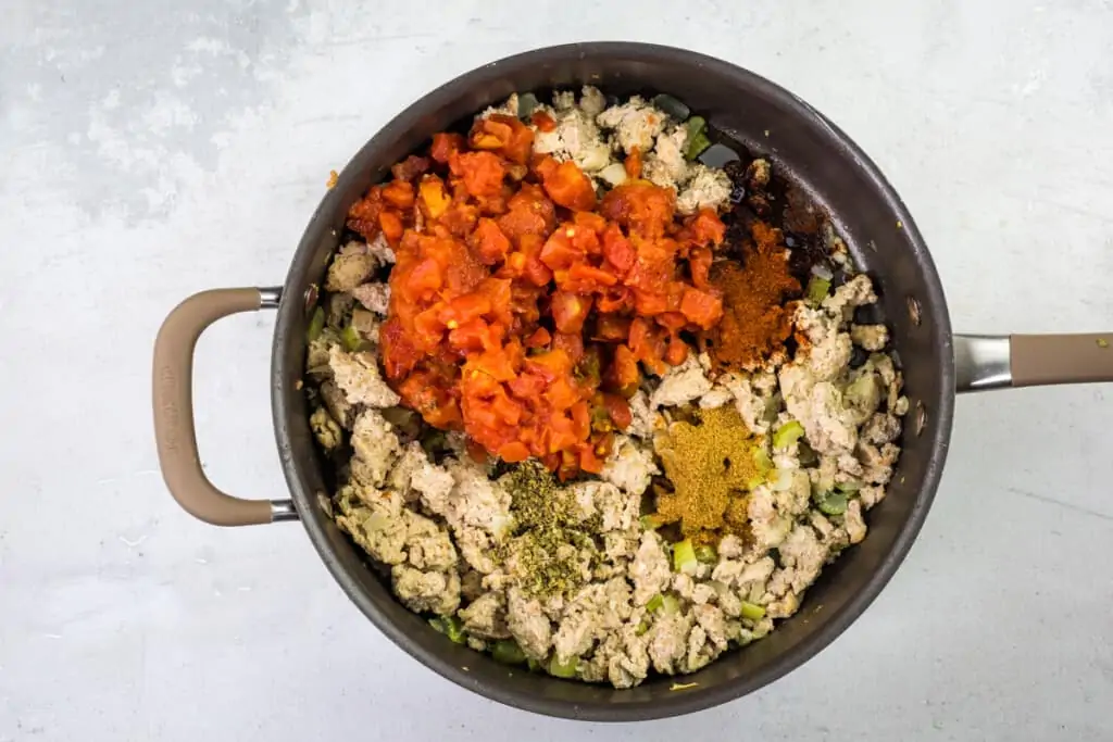 adding tomatoes to browned turkey and veggies