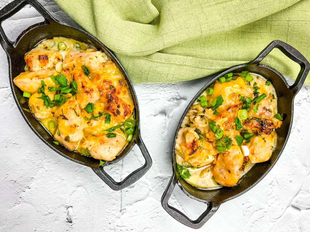 Two skillets filled with chicken and vegetables on a white background.