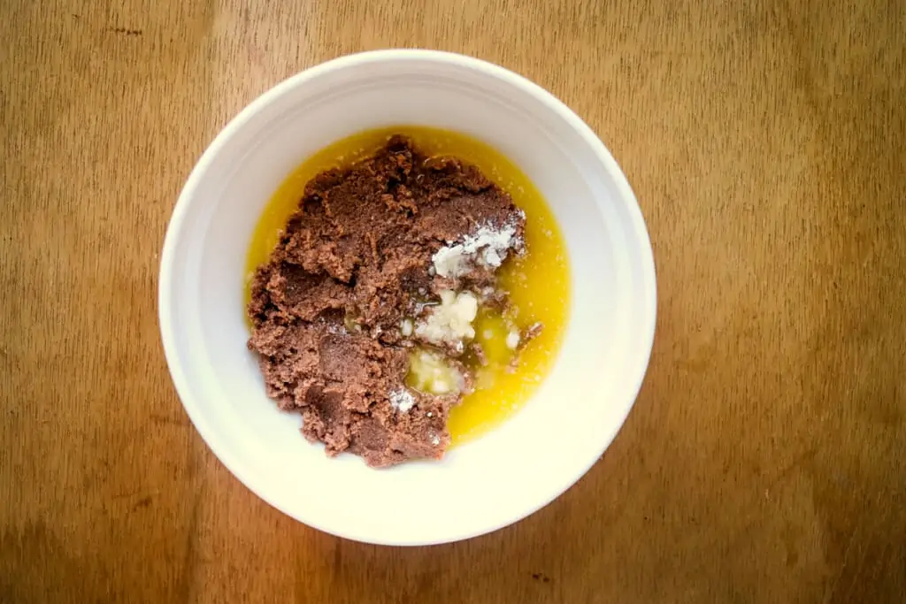 Adding melted butter to the peanut butter mixture.