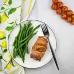 bacon wrapped cod and green beans on a white plate