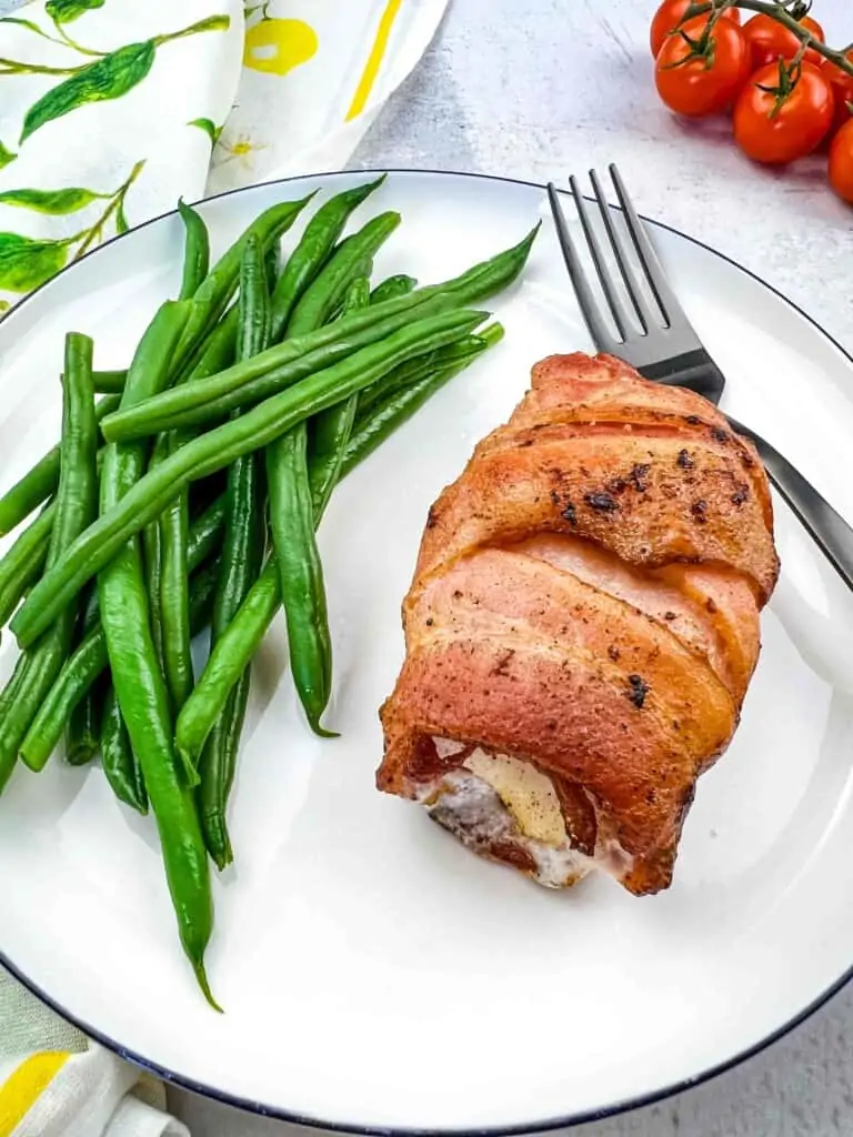 Keto bacon wrapped cod on a plate with green beans.