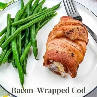 Bacon wrapped cod and green beans on a plate.