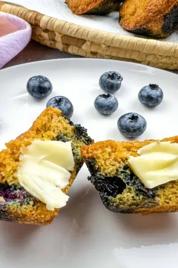 sliced keto blueberry muffins on a plate with butter