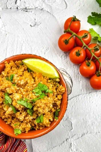 keto spanish rice in a serving dish with tomatoes on the side