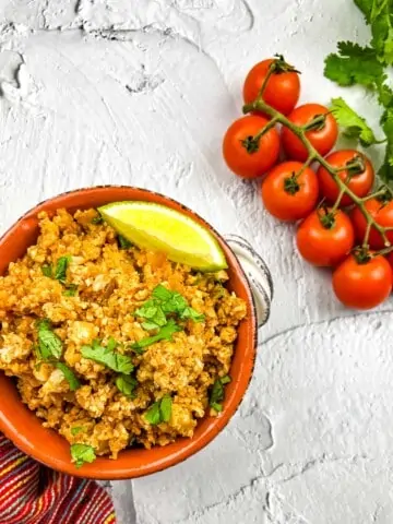 keto spanish rice in a serving dish with tomatoes on the side