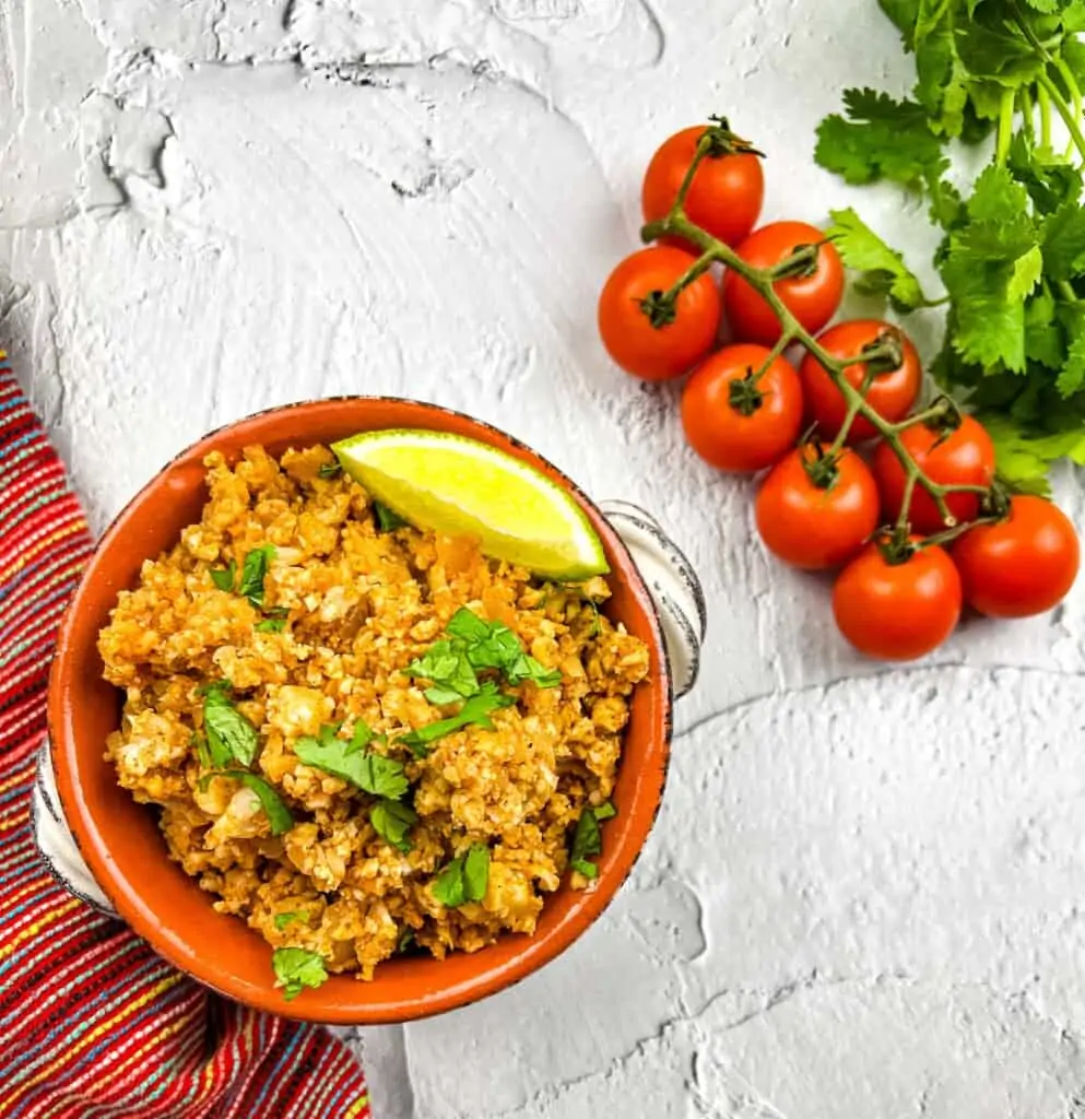 keto spanish rice in a serving dish with tomatoes on the side