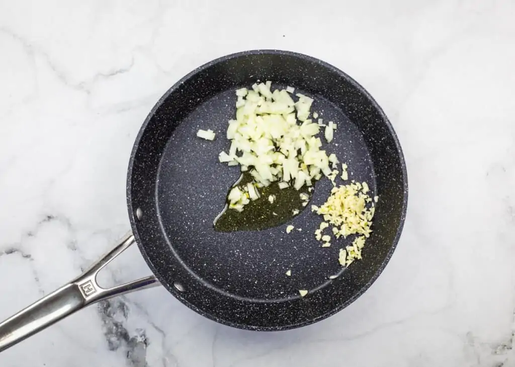 sauteeing onion and garlic in a pan to make keto spanish cauliflower rice