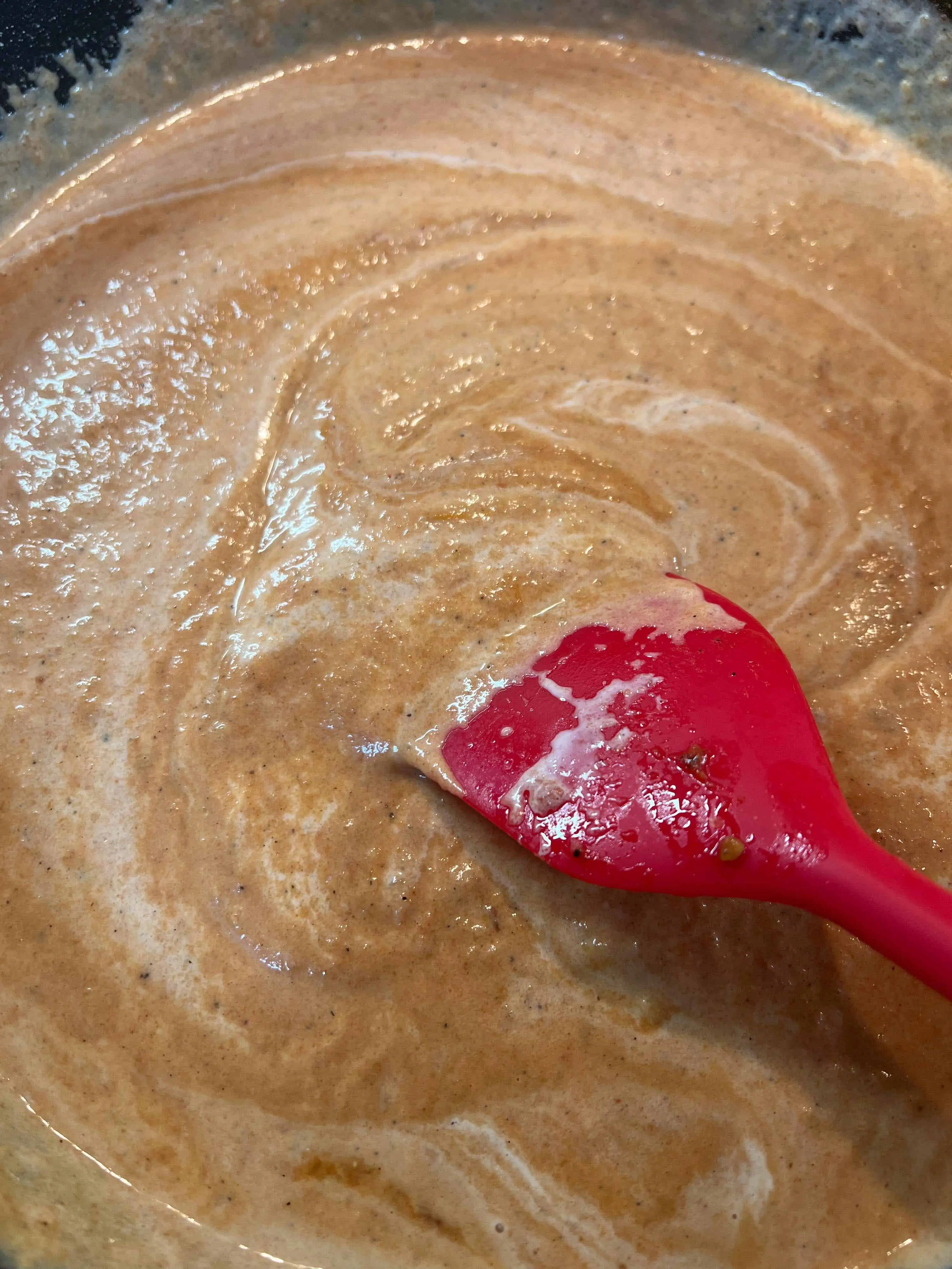 adding cream to pureed tomato and onion