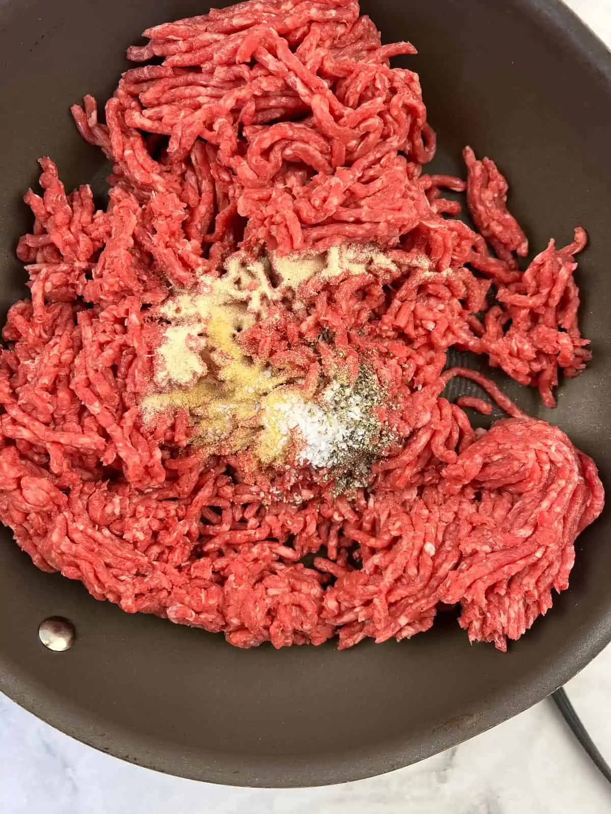 Cooking the beef and seasonings in a skillet.