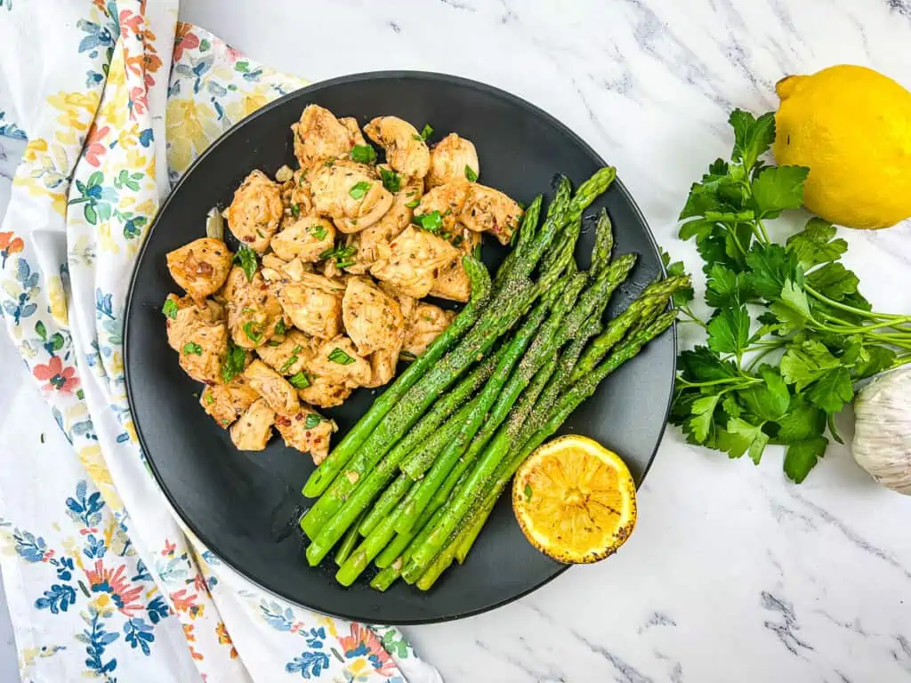keto garlic butter chicken bites with lemon asparagus on a plate