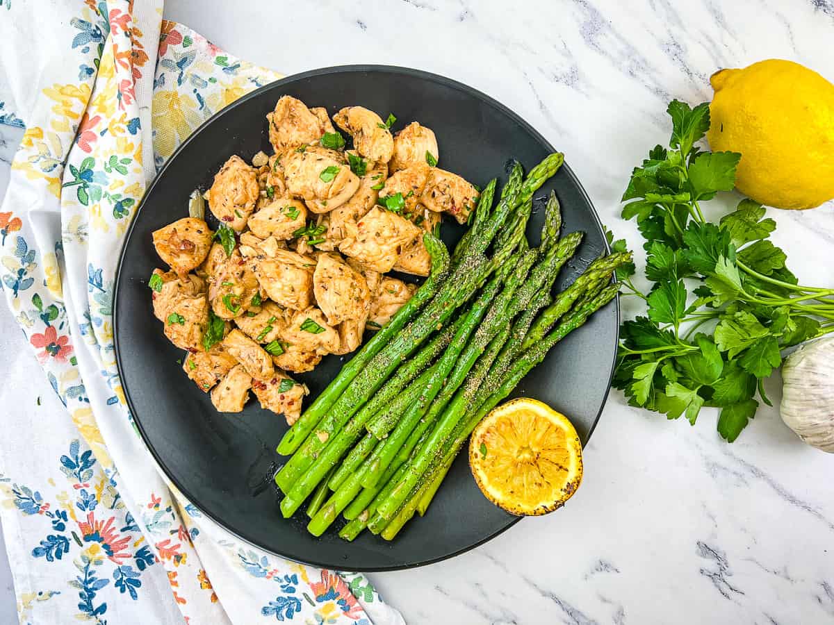A plate of Garlic Butter Chicken Bites with asparagus.