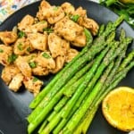 keto garlic butter chicken bites and lemon asparagus on a black plate