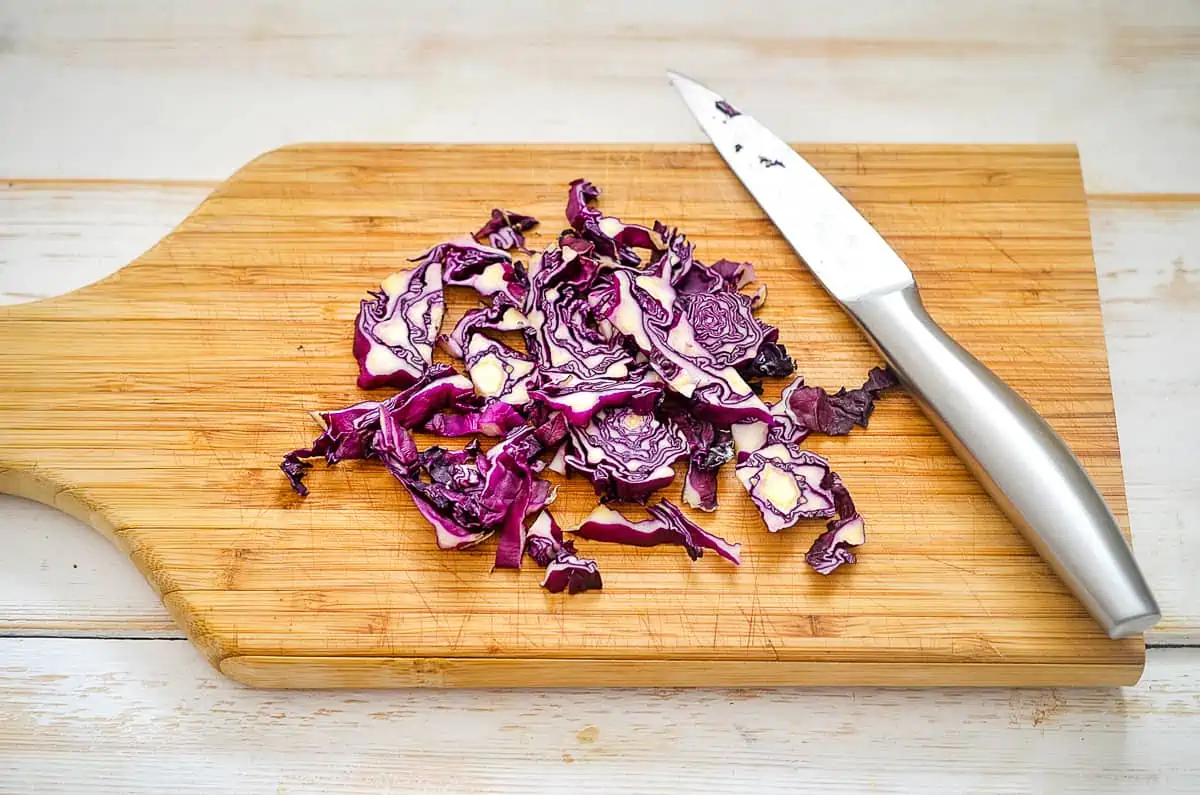 sliced red cabbage on a cutting board with a knife