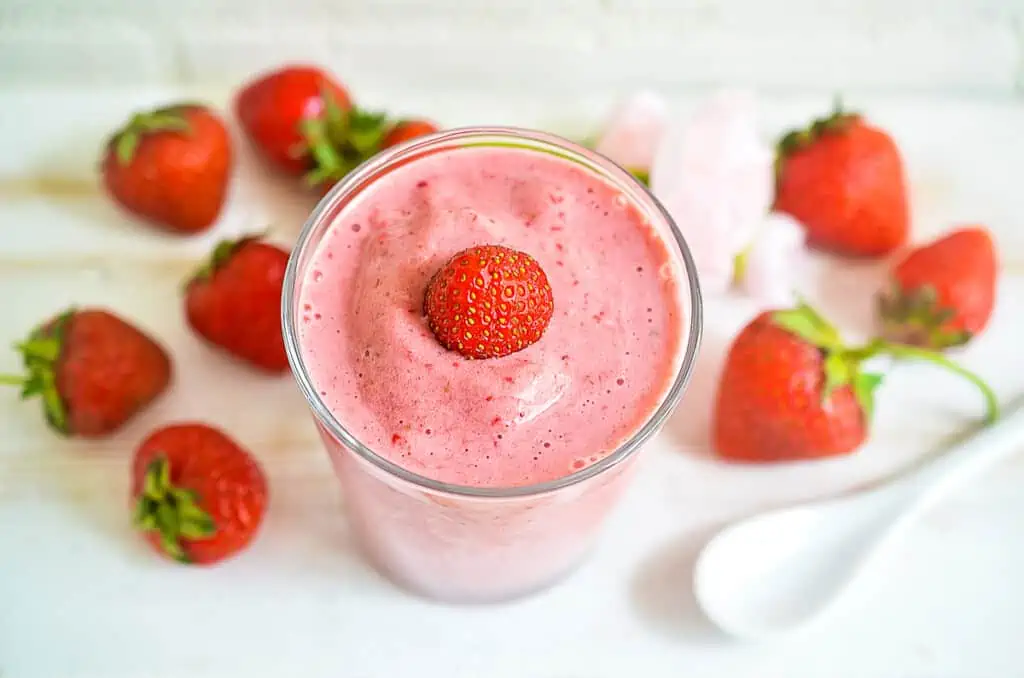 keto strawberry smoothie in a glass with strawberries nearby