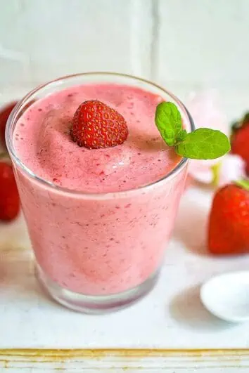 keto strawberry smoothie in a glass with strawberries around it