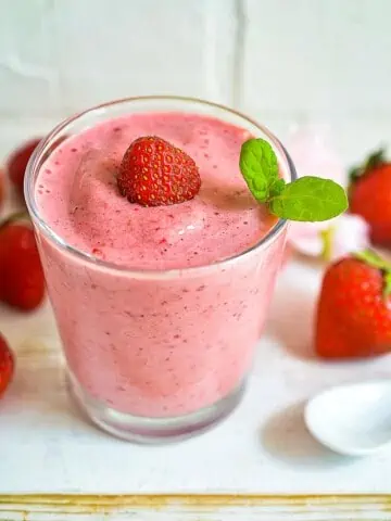 keto strawberry smoothie in a glass with strawberries around it