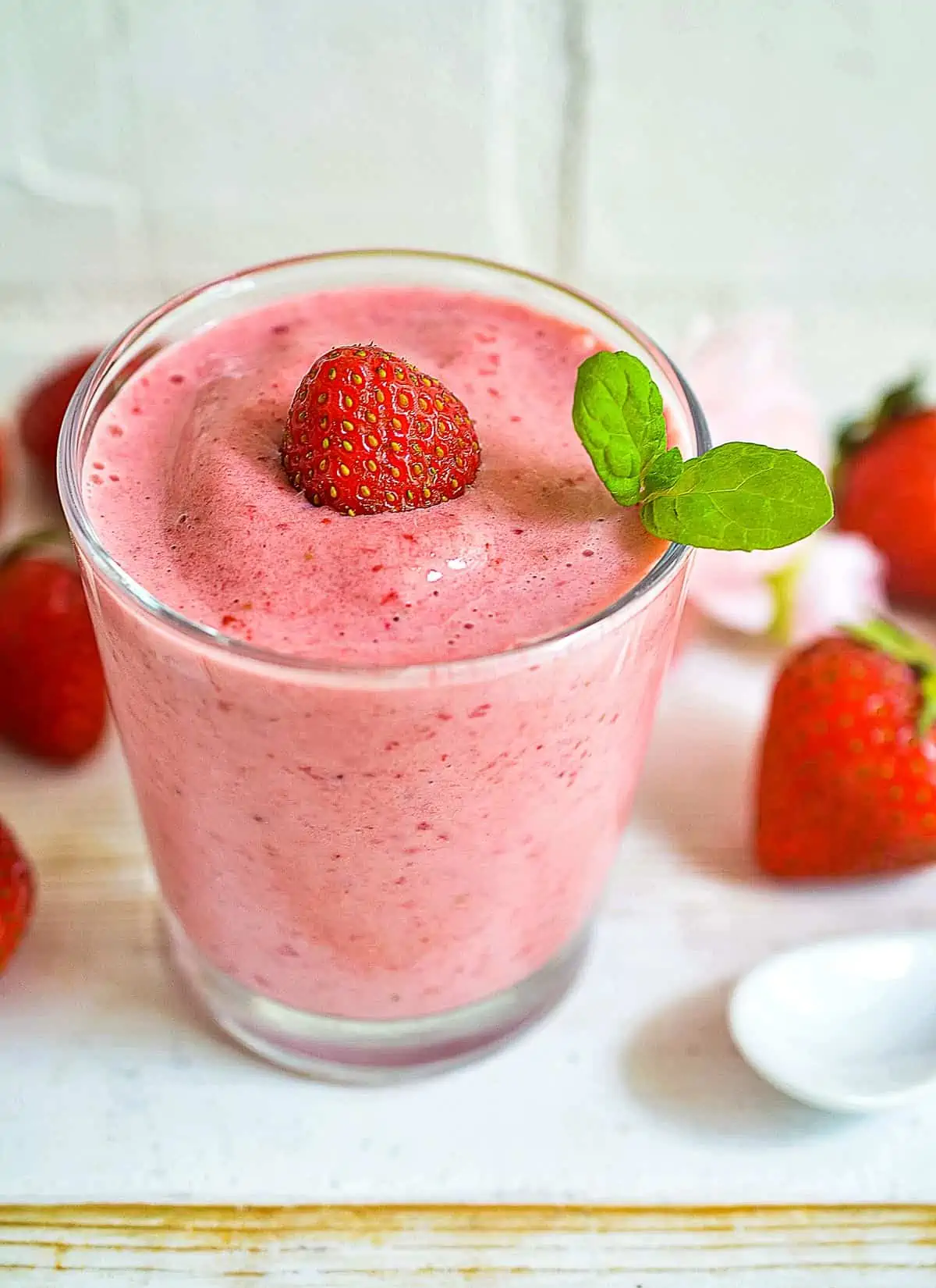 keto strawberry smoothie in a glass with strawberries around it