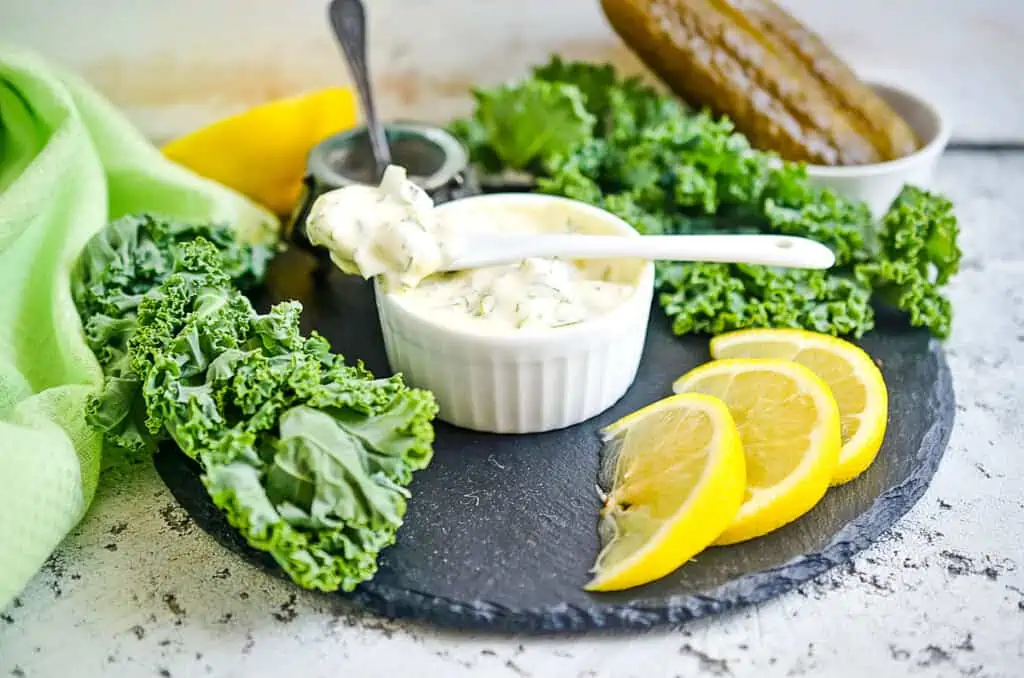 Keto tartar sauce finished and in a bowl on a black platter.