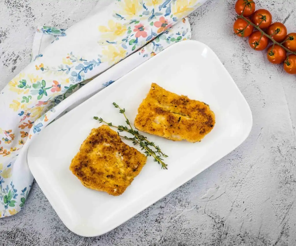 A top-down shot of keto pan fried cod on a white plate.