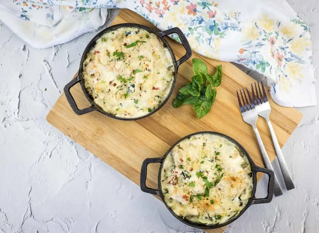 A top-down shot of keto chicken and zucchini casserole in two black dishes.