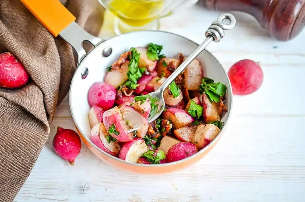 A top-down shot of keto Sauteed Radishes with Bacon in a skillet with a fork.
