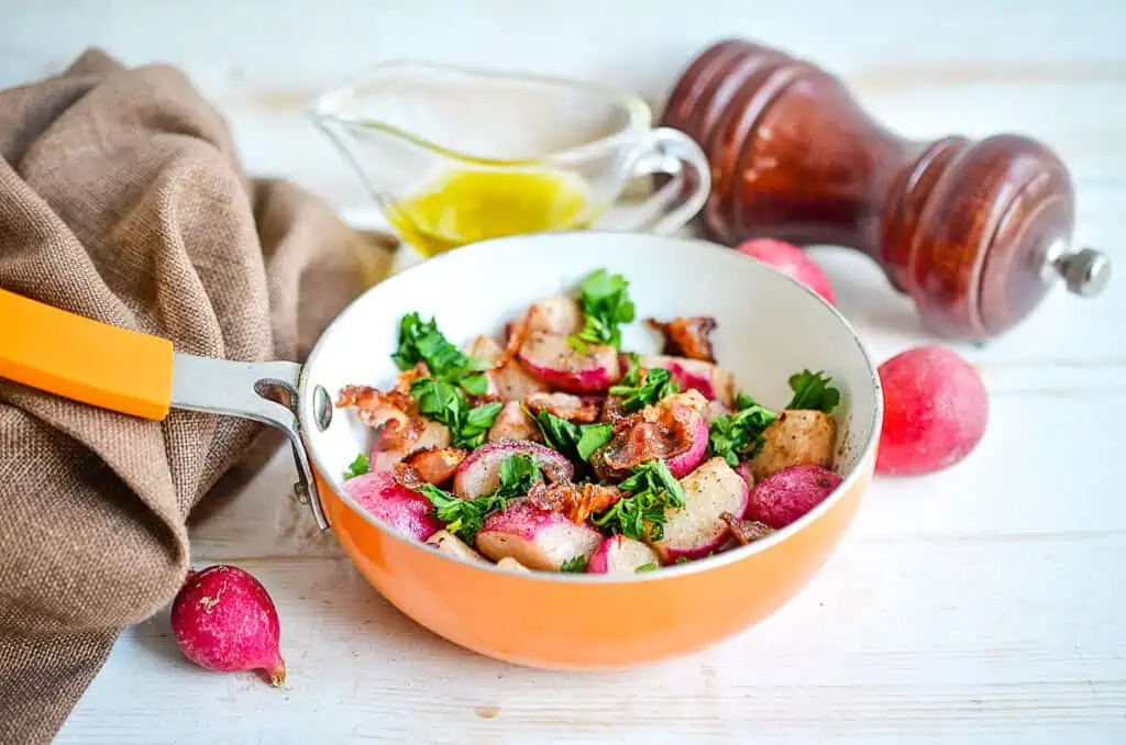 Sauteed Radishes topped with bacon and parsley in a skillet.