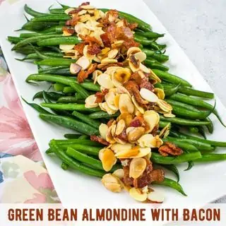 Green bean almondine with bacon on a white platter.
