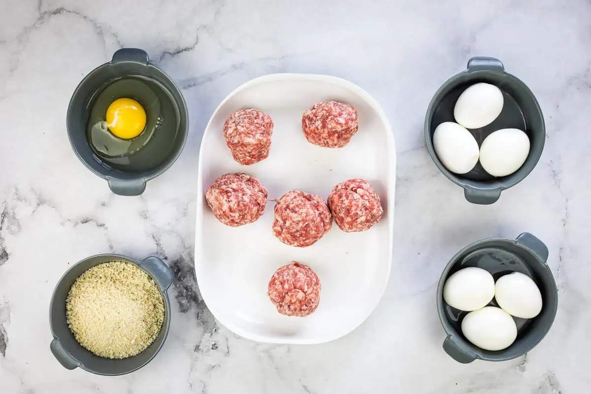 Peeled eggs, divided sausage, egg, and pork panko on the counter.