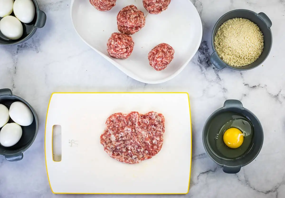 Flattened sausage ready to wrap the eggs.