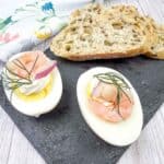 Two halves of Pickled Shrimp Egg Shooters beside bread on a slate plate.