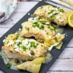 Skillet Chicken with Lemon, Artichokes & Feta on a black slate plate.