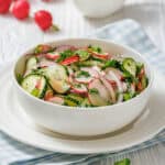 A bowl of radish salad featuring fresh radishes, cucumbers, and parsley, arranged attractively.