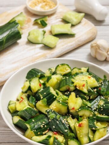 A bowl of cucumbers with sesame seeds and sesame oil.