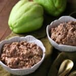 Two cups of Apple Cinnamon Oatmeal with two whole chayote squash and a gold spoon nearby on a wooden surface.
