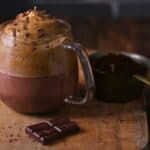 A cup of Dalgona Mocha Latte placed on a wooden board.