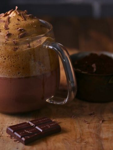 A cup of Dalgona Mocha Latte placed on a wooden board.