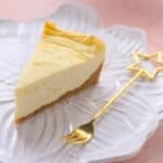 A slice of New York cheesecake is served alongside a star-shaped fork.