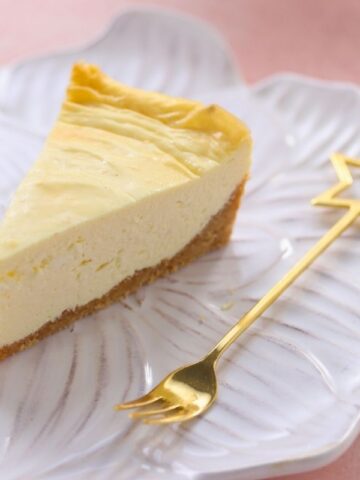 A slice of New York cheesecake is served alongside a star-shaped fork.